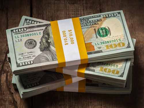 Stack of U.S. hundred dollar bills on wooden surface