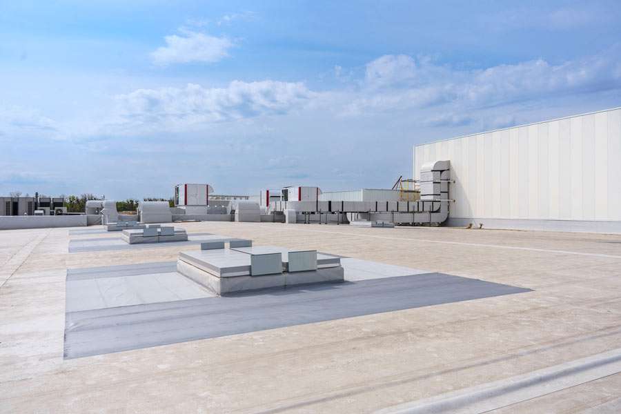 Industrial rooftop with HVAC units and sky.