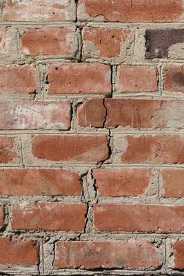 Weathered red brick wall with cracks.