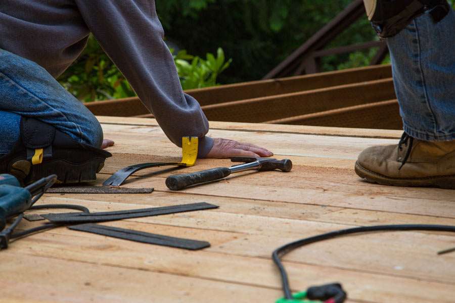Worker installing wooden floor with tools around.