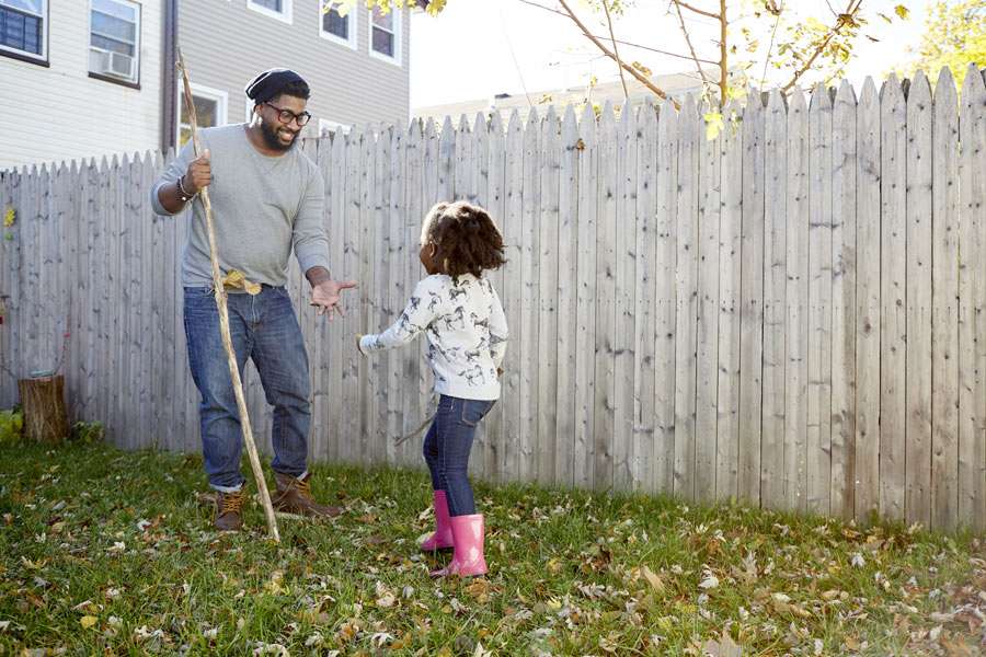 Father and daughter raking autumn leaves outdoors.