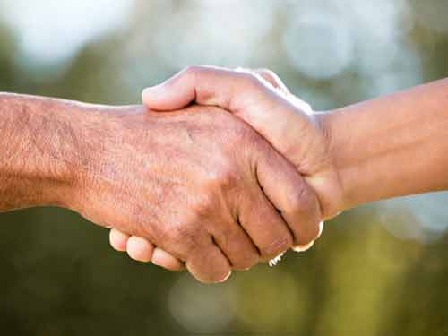 Two people shaking hands outdoors.