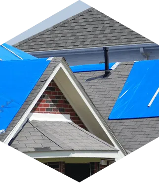 Roof damaged by storm covered with blue tarps.