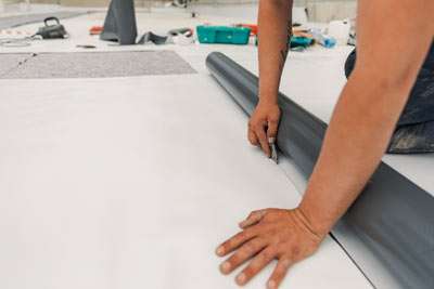 Person installing vinyl flooring with tools in background.