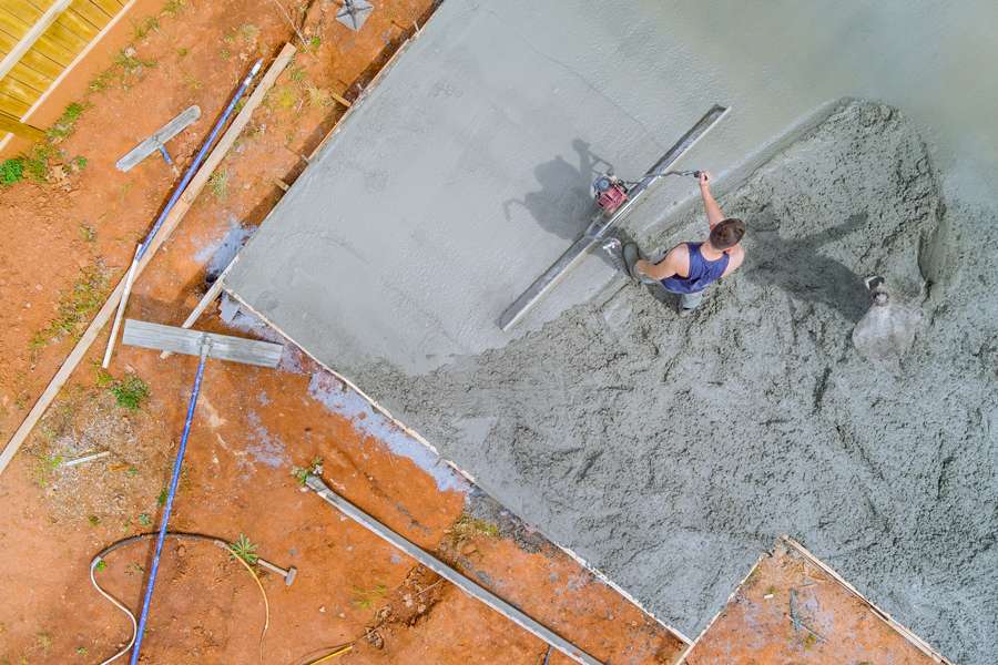 Worker smoothing concrete with trowel, aerial view.